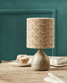 Flores 30cm Sable lampe de table De House Doctor - Il est doté d'une base en céramique couleur sable et d'un abat-jour en lin décoré de motifs de plumes de soleil sable et marron imprimés à la main, équilibrant magnifiquement une esthétique moderne et chaleureuse.