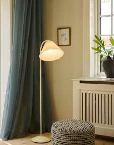 Medina Blanc crémeux lampadaire De Halo Design - Sa structure en métal blanc crème est mise en valeur par un magnifique abat-jour plissé en tissu assorti et des détails décoratifs en laiton.