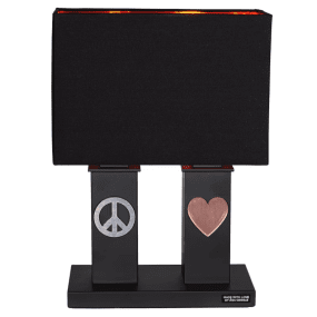 Stand By Me 50cm Noir lampe de table De By Rydéns - Le large abat-jour en tissu noir contraste avec les colonnes plus &eacute;troites de la base de la lampe, toutes deux d&eacute;cor&eacute;es d&#39;un symbole en m&eacute;tal, un signe de paix d&#39;un c&ocirc;t&eacute; et un c&oelig;ur de l&#39;autre.