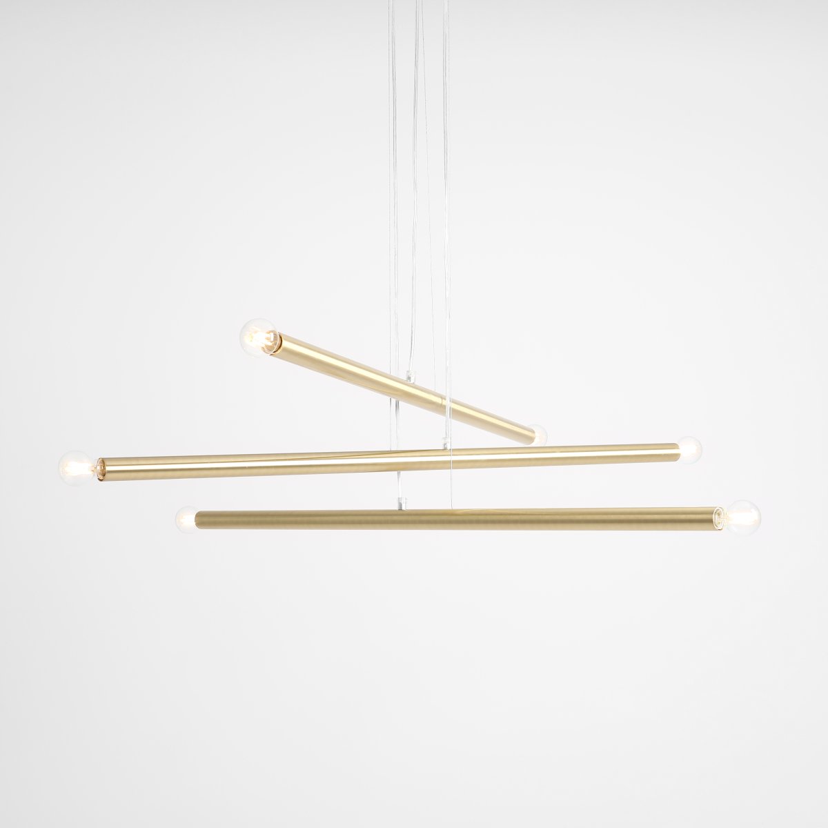 Tubo 6 100cm Laiton suspension De Artera - Elle se compose de trois fins tubes métalliques à la finition laiton élégante, disposés à différentes hauteurs et angles pour créer un effet dynamique et aérien.