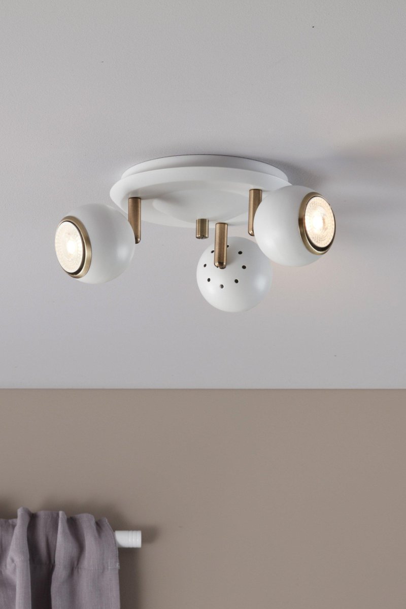 Coco 3 Blanc spot De Markslöjd - Les têtes de lampe blanches et rondes combinées à des détails en métal de couleur antique créent une expression sophistiquée et élégante qui est parfaite pour les salons, les cuisines ou les espaces de travail.