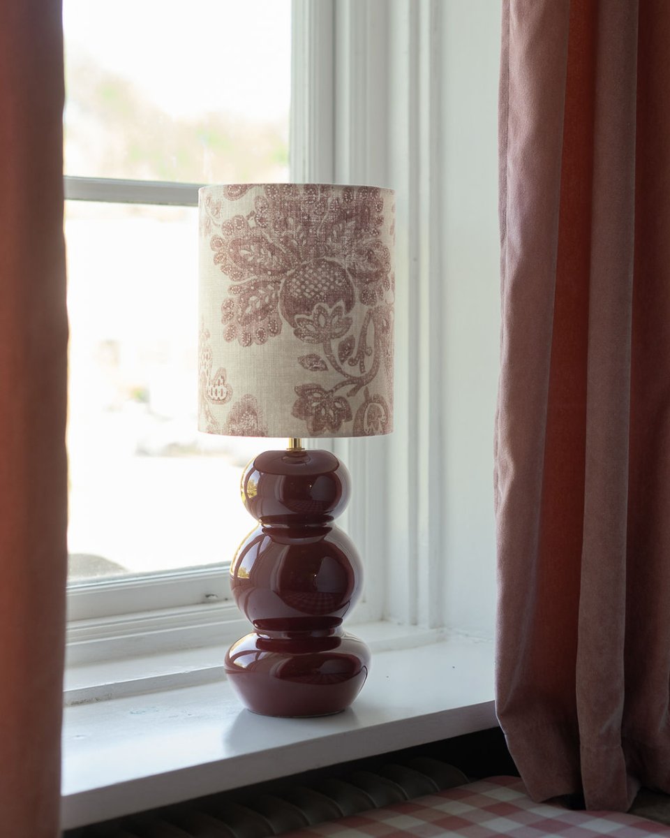 Lampshade Cylinder Sunshine Ø22 rouge foncé De Alde & Lind - Confectionné dans un mélange de lin orné d'un magnifique motif décoratif, il associe une couleur de fond claire à un motif floral détaillé dans des tons terreux foncés et feutrés, conférant à l'abat-jour une allure chaleureuse et douce.