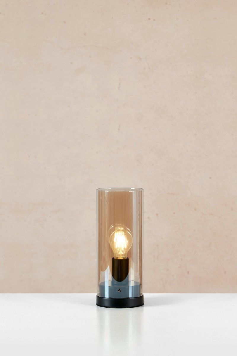 Post 38cm Ambre lampe de table De Markslöjd - Post est une &eacute;l&eacute;gante lampe de table cylindrique avec une base en m&eacute;tal noir mat et un abat-jour en verre ambr&eacute;.
