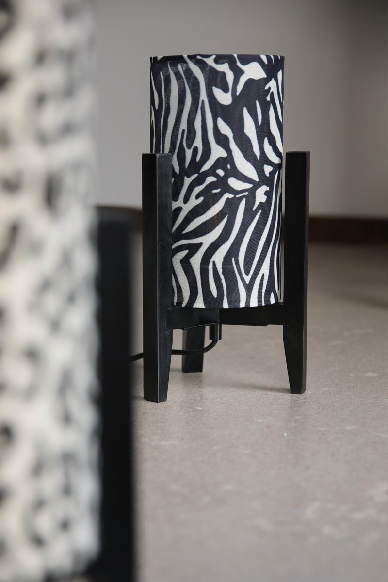 Eruca 34cm Zèbre lampe de table De Markslöjd - Son pied en bois noir s'harmonise parfaitement avec son abat-jour cylindrique en tissu &agrave; motif z&egrave;bre noir et blanc, conf&eacute;rant &agrave; la lampe un caract&egrave;re graphique et expressif.