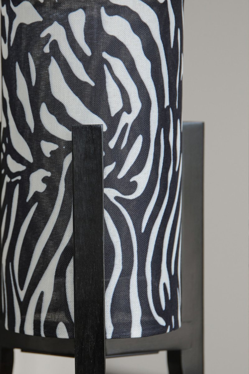 Eruca 34cm Zèbre lampe de table De Markslöjd - Son pied en bois noir s'harmonise parfaitement avec son abat-jour cylindrique en tissu &agrave; motif z&egrave;bre noir et blanc, conf&eacute;rant &agrave; la lampe un caract&egrave;re graphique et expressif.