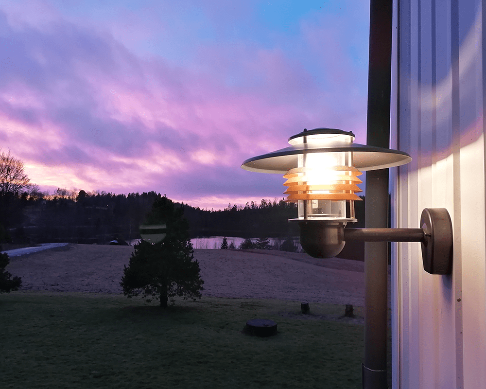 Arnäs Cuivre oxydé lampe d’extérieur De Westal - L'applique murale Arns est une lampe élégante avec un motif lumineux rond et un abat-jour en verre transparent entourant la source lumineuse.
