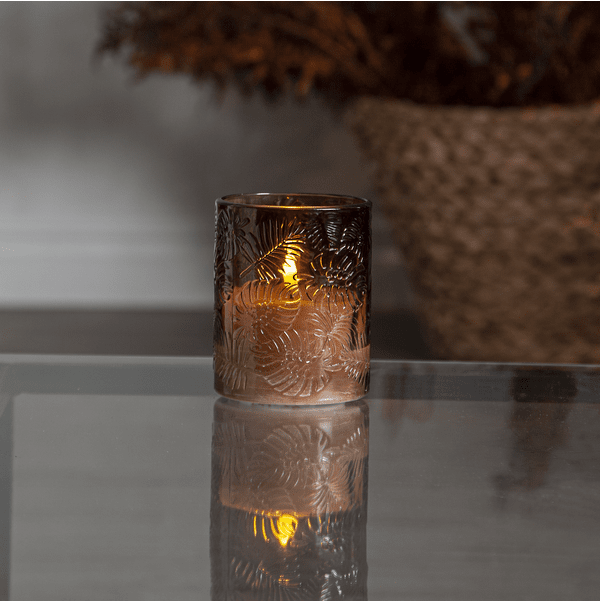 LED Bougie Flamme Leaf Brun De Star Trading - Flamme Leaf est une lanterne en verre à piles en verre brun avec un motif de feuille en relief autour d'une bougie en cire blanche.