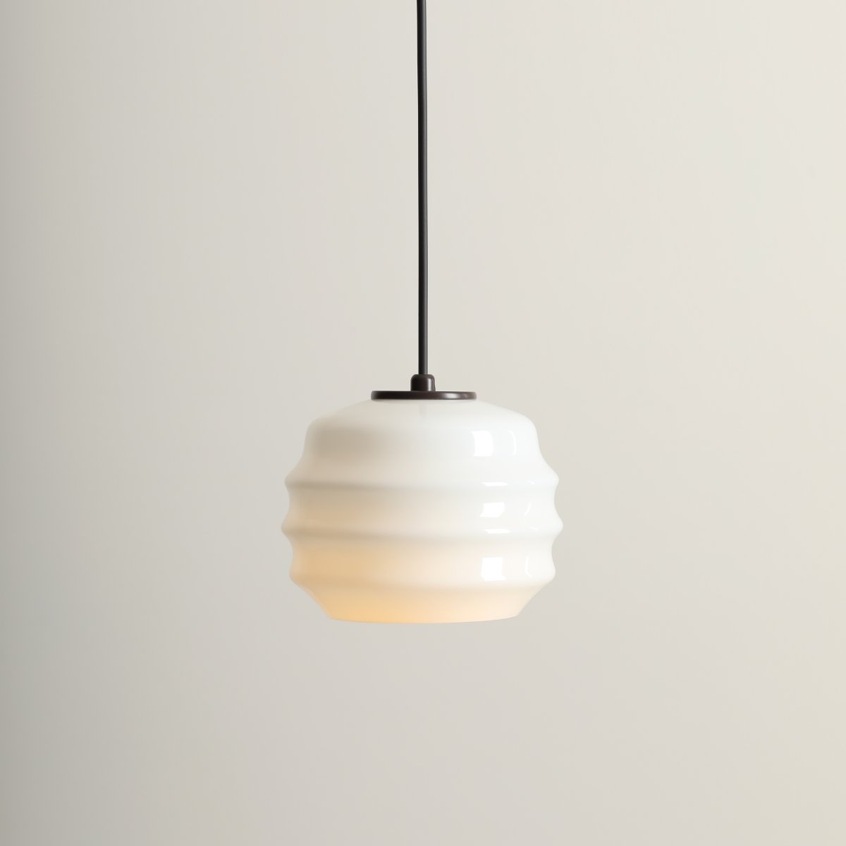 Puff Ø16 brun foncé suspension De Artera - Son abat-jour décoratif en verre opale blanc séduit par sa forme incurvée, conférant à la lampe une allure à la fois ludique et raffinée.