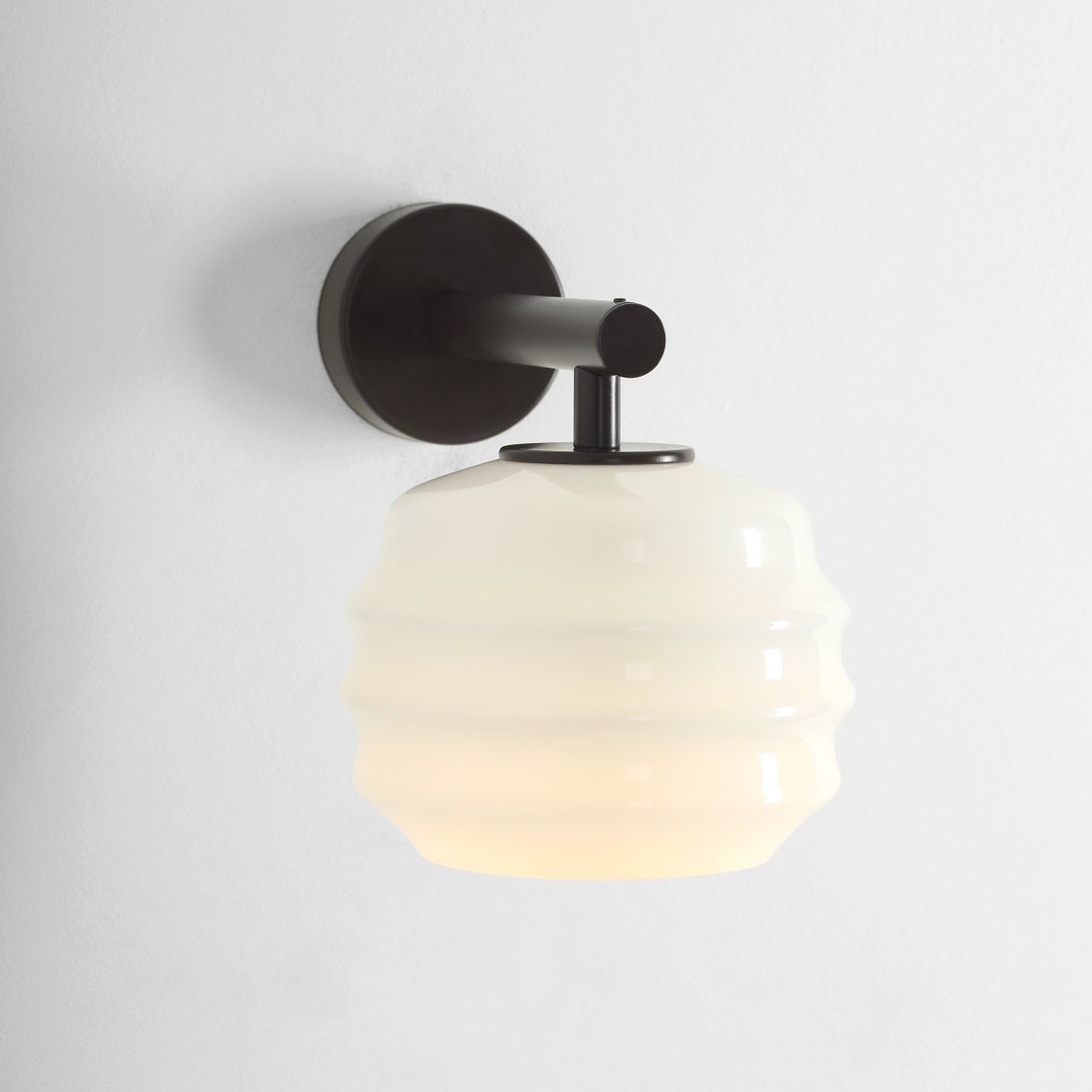 Puff 23cm brun foncé applique murale De Artera - Son abat-jour décoratif en verre opale blanc séduit par sa forme incurvée, conférant à la lampe une allure à la fois ludique et raffinée.