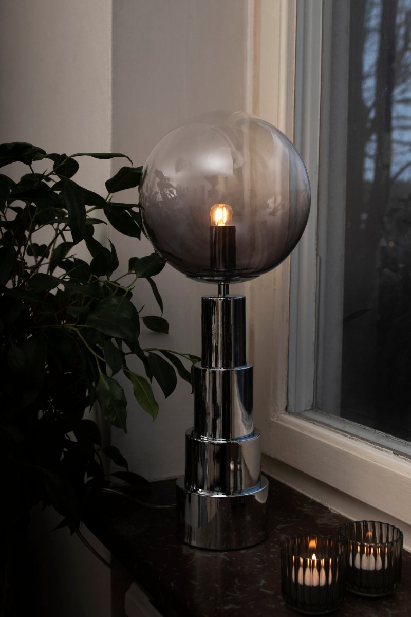 Astro 48cm Chrome lampe de table De Globen Lighting - La lampe est fabriquée en métal de couleur chrome et possède un globe en verre teinté de fumé à transparent.