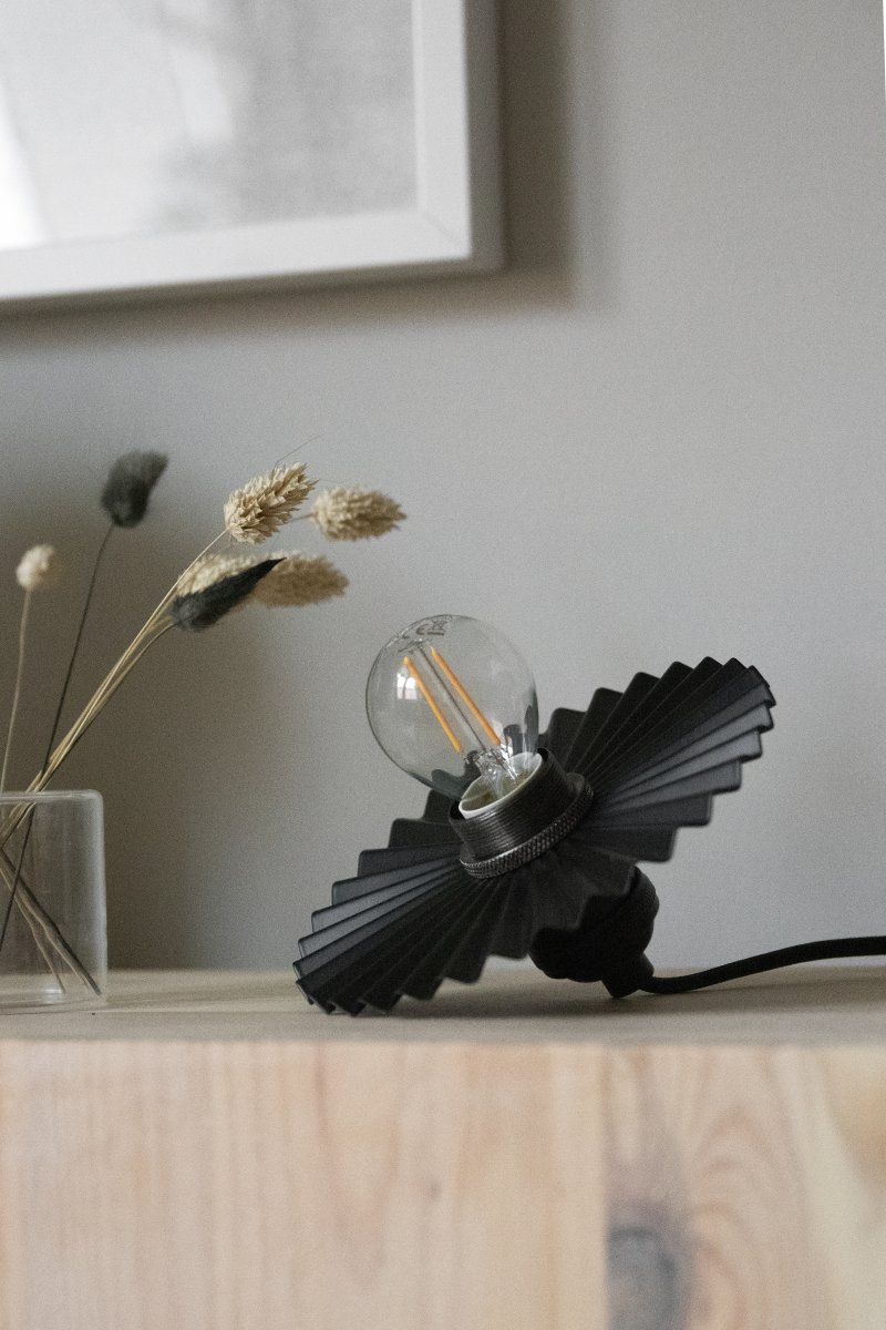 Omega Ø15 Noir lampe de fenêtre De Globen Lighting - Elle peut également être placée horizontalement sur une étagère ou une commode pour apporter une touche décorative.