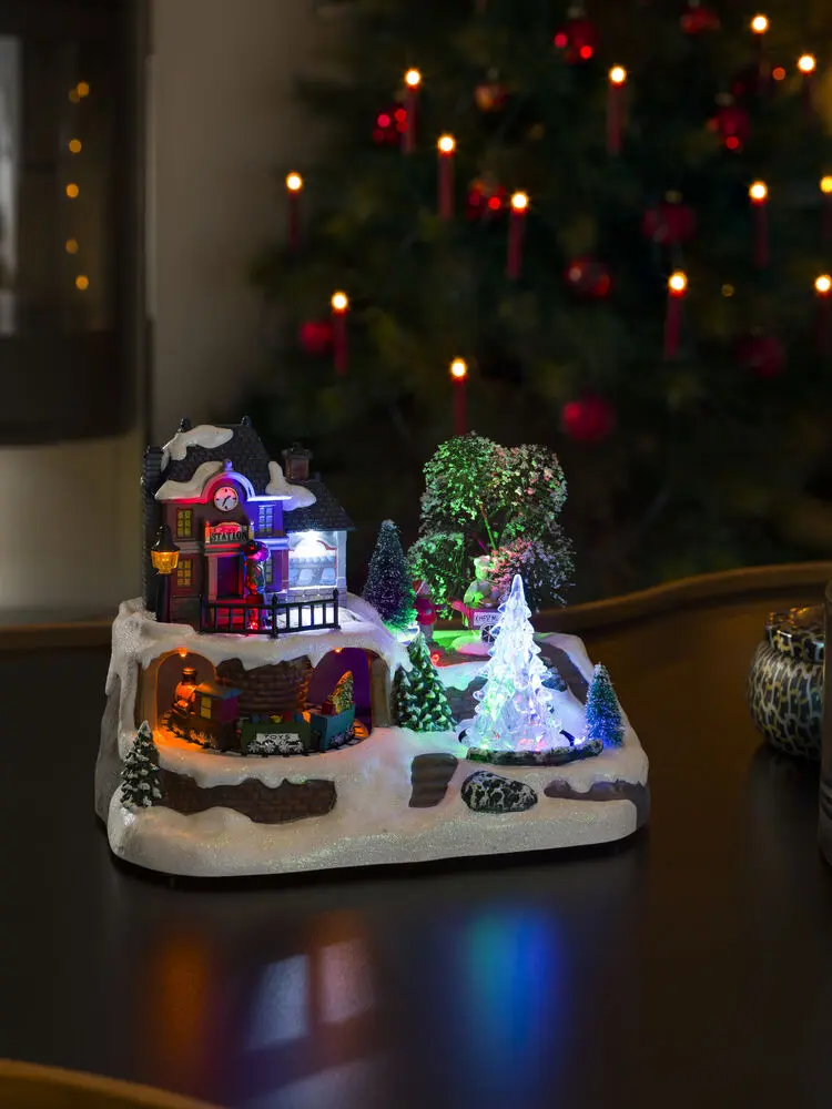 Décoration De Noël Mécanique Avec Gare 17cm Multicolore De Konstsmide - Des lumi&egrave;res LED lumineuses et de la musique int&eacute;gr&eacute;e cr&eacute;ent une merveilleuse atmosph&egrave;re de No&euml;l tandis que le train fait le tour des d&eacute;corations.