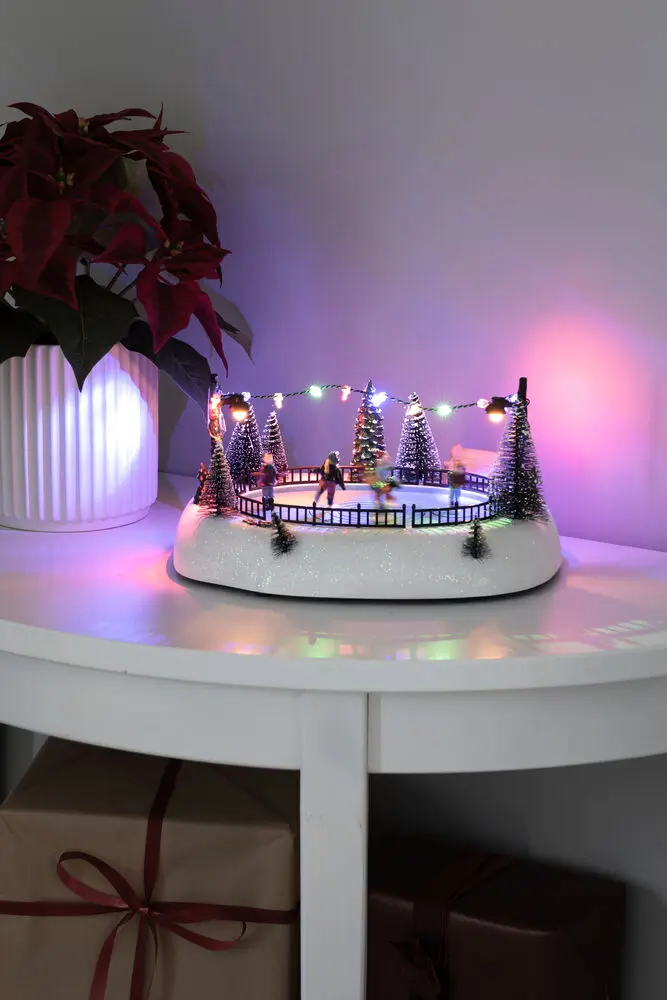 Décoration De Noël Mécanique Avec Patinoire 13cm Multicolore De Konstsmide - Apportez du mouvement et de la joie &agrave; votre village de No&euml;l avec des sapins, des guirlandes lumineuses et un paysage hivernal.