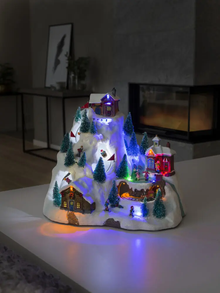 Décoration De Noël Mécanique Avec Paysage Montagneux 28cm Multicolore De Konstsmide - La sc&egrave;ne de montagne enneig&eacute;e s'illumine avec de belles lumi&egrave;res LED, des d&eacute;tails en mouvement et joue 8 chansons de No&euml;l classiques.