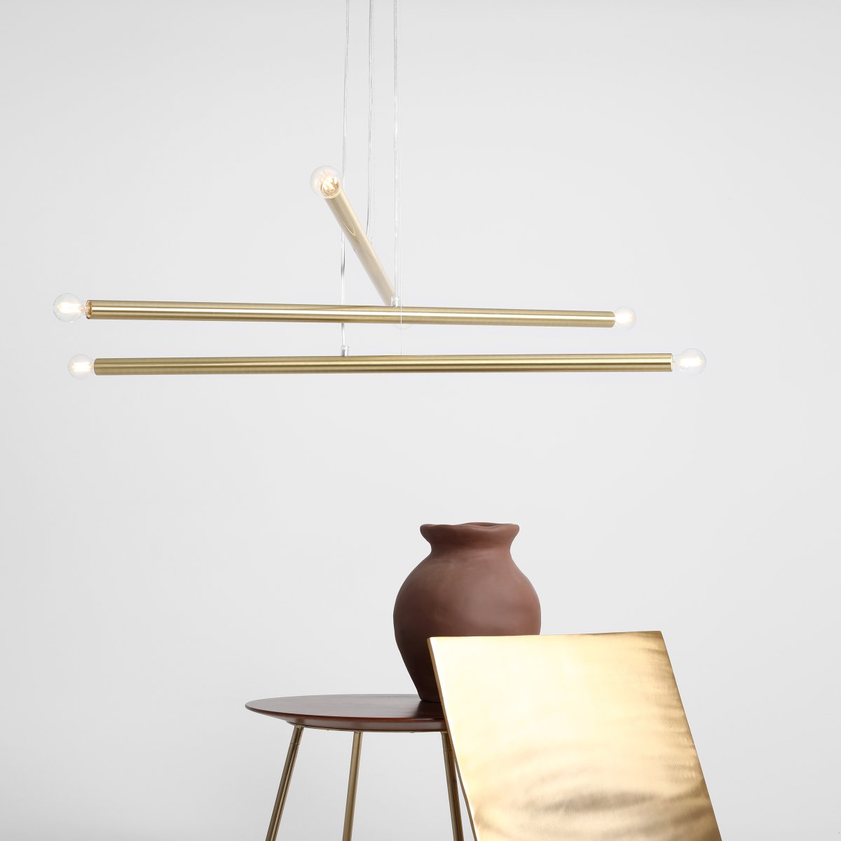 Tubo 6 100cm Laiton suspension De Artera - Elle se compose de trois fins tubes métalliques à la finition laiton élégante, disposés à différentes hauteurs et angles pour créer un effet dynamique et aérien.