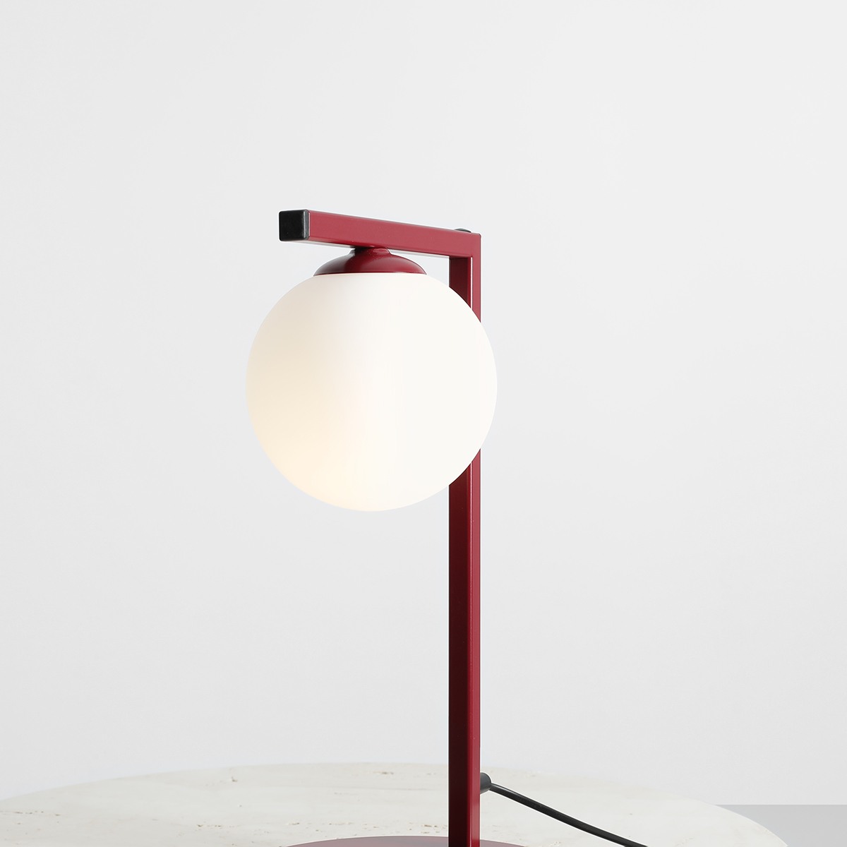 Zac 50cm Bourgogne lampe de table De Artera - La lampe de table Zac en métal bordeaux et verre blanc présente un design moderne et minimaliste qui allie élégance et fonctionnalité.