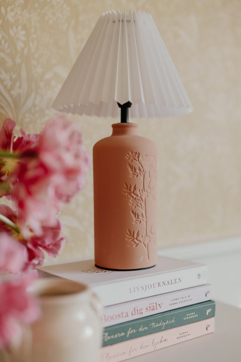 Flora 40cm Terre cuite lampe de table De Globen Lighting - Comme joli d&eacute;tail, un motif de fleur de prunellier est press&eacute; sur un c&ocirc;t&eacute; de la base de la lampe, lui donnant une v&eacute;ritable touche d'artisanat.
