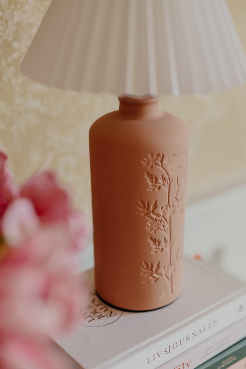 Flora 40cm Terre cuite lampe de table De Globen Lighting - Comme joli d&eacute;tail, un motif de fleur de prunellier est press&eacute; sur un c&ocirc;t&eacute; de la base de la lampe, lui donnant une v&eacute;ritable touche d'artisanat.