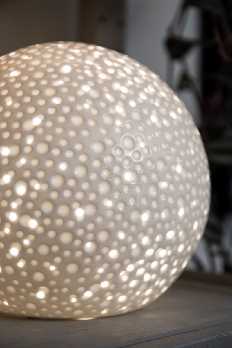 Moonlight 20cm Blanc lampe de table De Globen Lighting - La surface de cette lampe de table un peu plus moderne présente des trous perforés de différentes tailles ainsi que des cratères qui rappellent l'apparence des hommes.