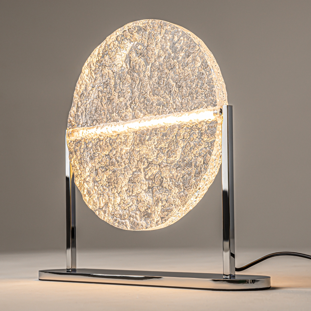Mangata 30cm Transparent lampe de table De Maytoni - Son pied en m&eacute;tal chrom&eacute; lui conf&egrave;re un style &eacute;l&eacute;gant et exclusif, tandis que son abat-jour en acrylique transparent &agrave; la surface textur&eacute;e diffuse la lumi&egrave;re de mani&egrave;re d&eacute;corative.