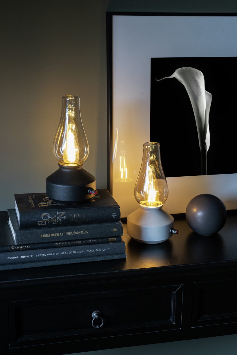 Lampe de table rechargeable 25cm Blanc portable De Konstsmide - Fabriquée en métal et en verre, elle est dotée d'un socle blanc et d'un variateur pratique permettant de régler facilement l'intensité de sa lumière blanche chaude et tamisée.