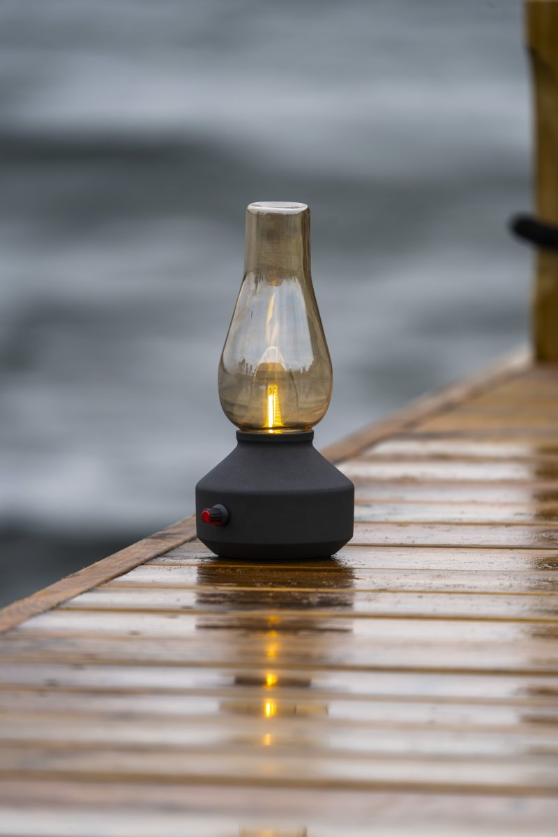 Lampe de table rechargeable 25cm Noir portable De Konstsmide - Fabriquée en métal et en verre, elle est dotée d'un socle noir et d'un variateur pratique permettant de régler facilement l'intensité de sa lumière blanche chaude et tamisée.