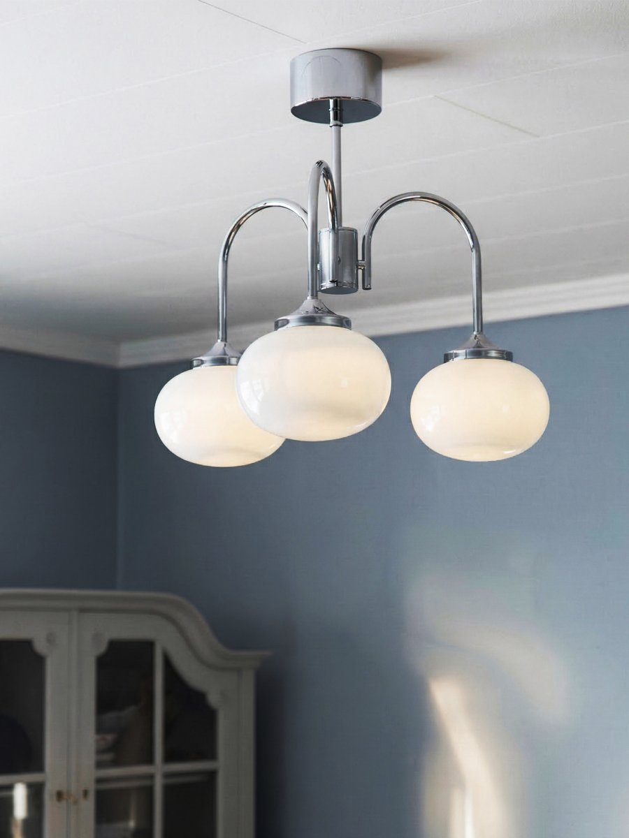 Elsy Ø52 Chrome plafonnier De PR Home - Il est dot&eacute; de trois bras orient&eacute;s vers le bas, surmont&eacute;s d'abat-jour en verre blanc qui diffusent une lumi&egrave;re douce et agr&eacute;able, cr&eacute;ant une ambiance cosy dans les salons, salles &agrave; manger ou couloirs.