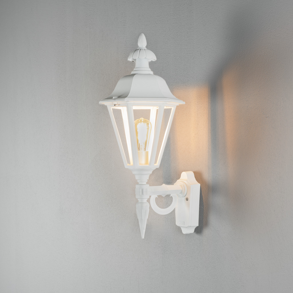 Pallas Blanc lampe d’extérieur De Konstsmide - Avec sa conception en forme de lanterne et ses panneaux en verre transparent, la lampe émet une lumière chaleureuse et invitante, parfaite pour les entrées, les patios et les allées.