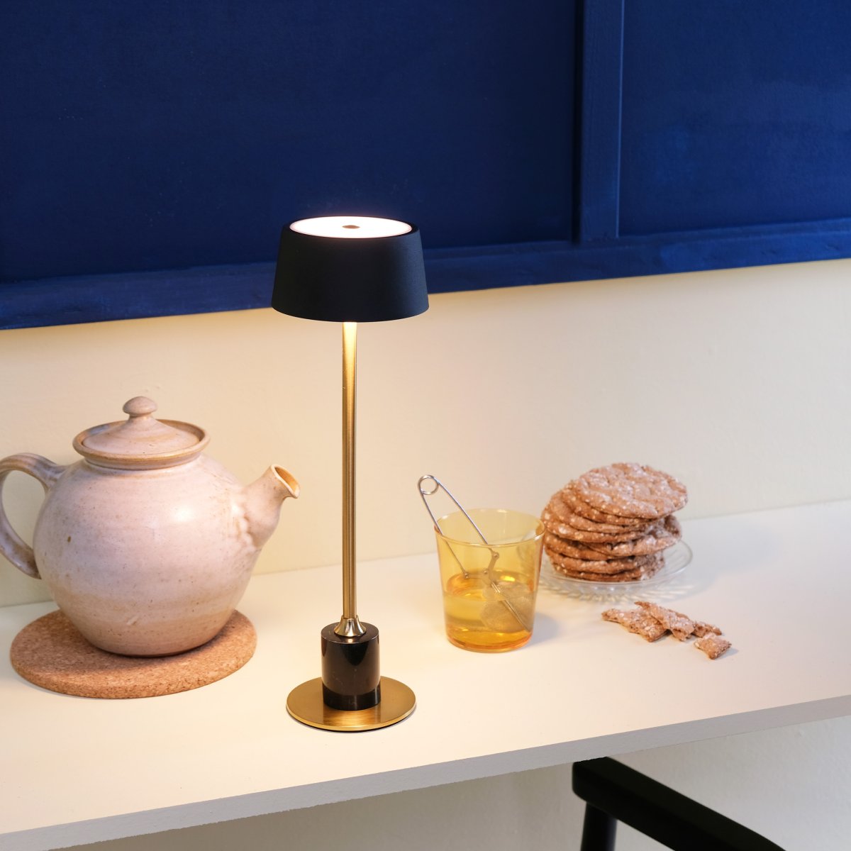 Yoyo LED 33cm Laiton portable De Dyberg Larsen - La fonction tactile douce sur le dessus contr&ocirc;le trois niveaux d'&eacute;clairage et le rend parfait pour les endroits avec un espace limit&eacute; - par exemple sur un rebord de fen&ecirc;tre &eacute;troit, sur une table plus petite ou en groupe sur la table &agrave; manger pour une d&eacute;coration de table &eacute;l&eacute;gante.