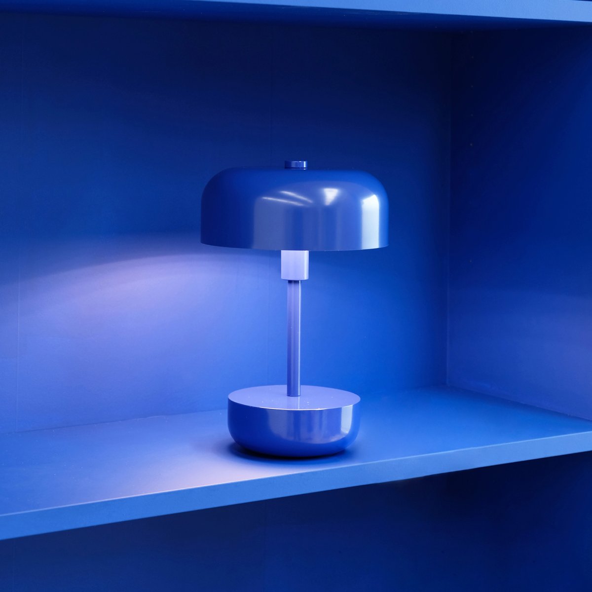 Haipot 25cm Bleu portable De Dyberg Larsen - La conception ouverte de l'abat-jour assure une belle réflexion de la lumière qui met en valeur la couleur de la base, et lorsque l'obscurité tombe, la lampe crée un jeu de lumière atmosphérique.