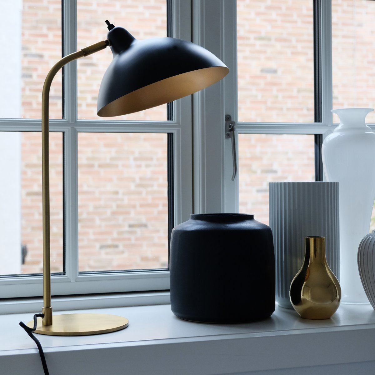 Futura 55cm Laiton lampe de table De Dyberg Larsen - La surface noire et l'int&eacute;rieur couleur laiton antique de l'abat-jour diffusent une lumi&egrave;re chaleureuse et cr&eacute;ent une belle atmosph&egrave;re dans la maison.