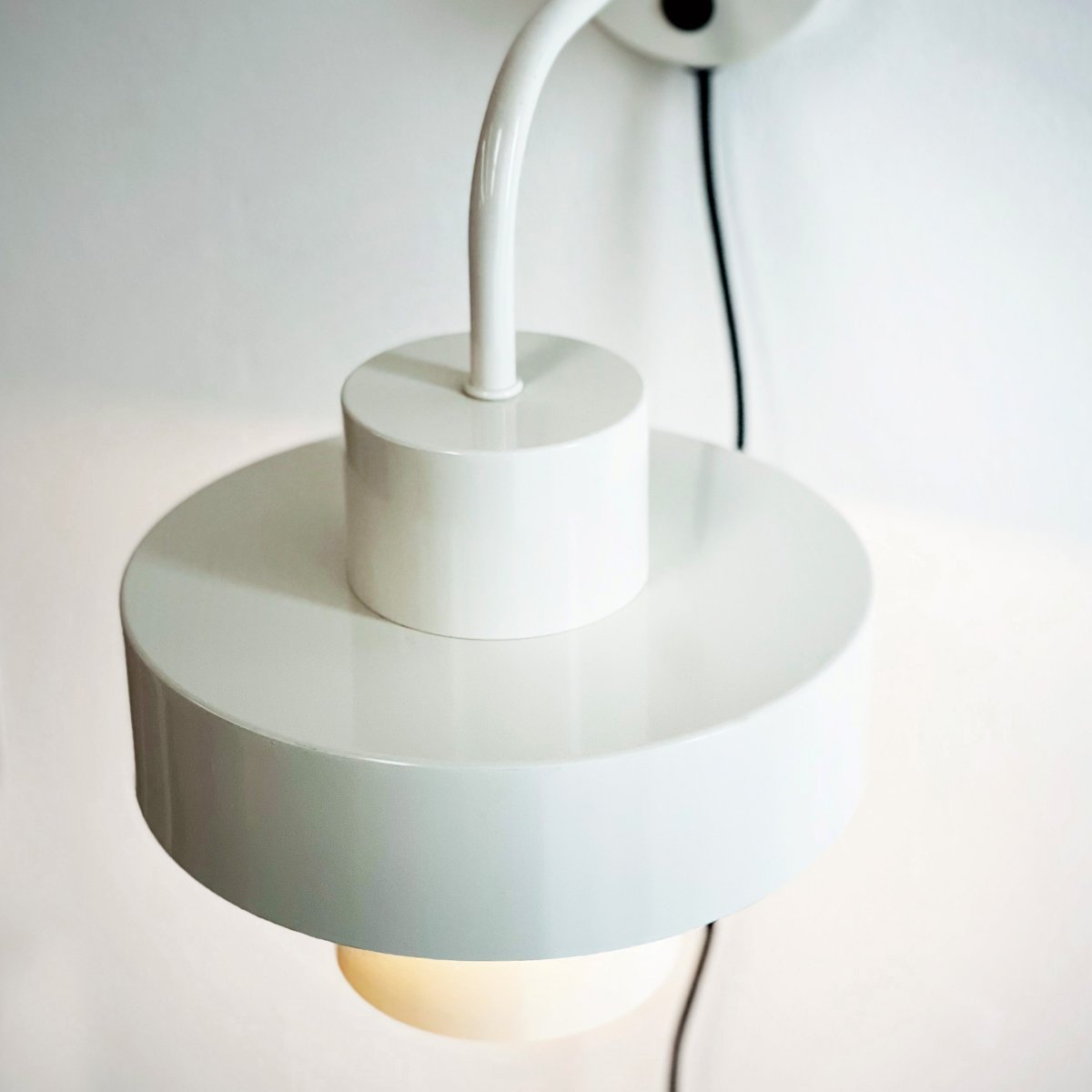 Stoke Ø15 Blanc applique murale De Dyberg Larsen - Il est fabriqué en métal avec une surface brillante qui met en valeur les formes cylindriques de la lampe et crée un contraste équilibré avec d'autres matériaux tels que la pierre, le bois et le verre.