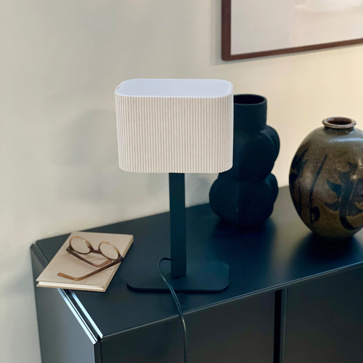 Calix Ovale 40cm Noir lampe de table De Dyberg Larsen - Den ribbade, naturf&auml;rgade sk&auml;rmen av textil medf&ouml;r en v&auml;rme till rummet och i kombination med den svarta metallfoten passar Calix in i alla stilar och hem.