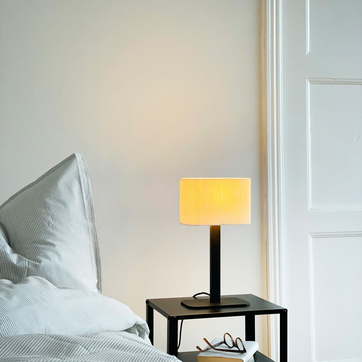 Calix Ovale 40cm Noir lampe de table De Dyberg Larsen - Den ribbade, naturf&auml;rgade sk&auml;rmen av textil medf&ouml;r en v&auml;rme till rummet och i kombination med den svarta metallfoten passar Calix in i alla stilar och hem.