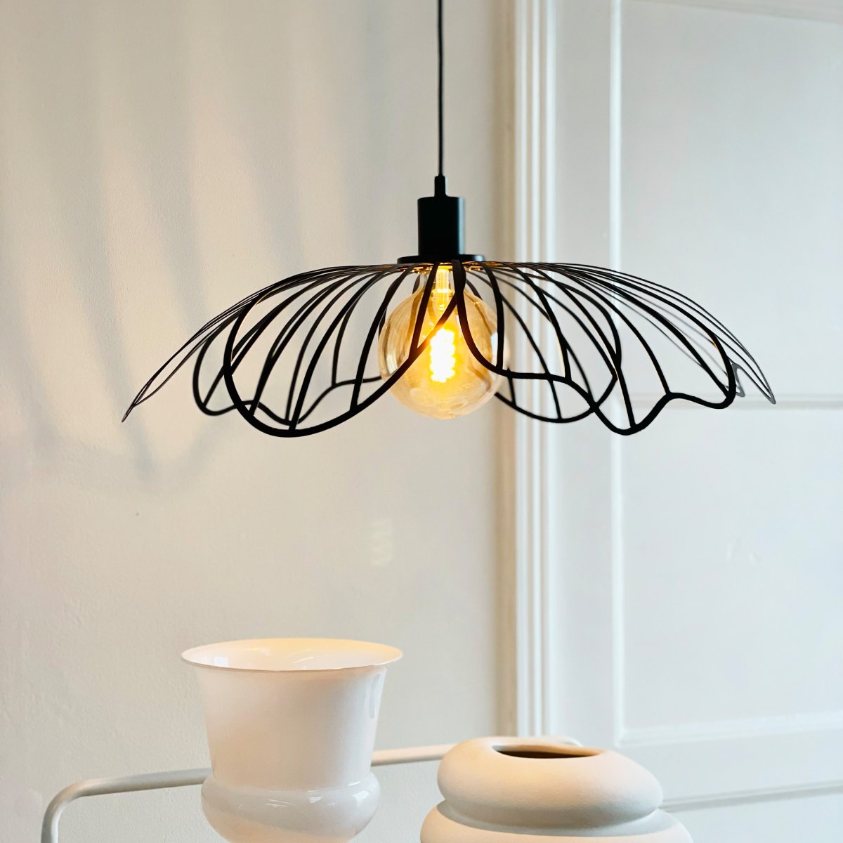 Blumen Ø60 Noir mat suspension De Dyberg Larsen - Den sprider ett sofistikerat ljus och fungerar som en unik mittpunkt i hemmet, vare sig den h&auml;nger &ouml;ver matbordet, i vardagsrummet eller i entr&eacute;n.