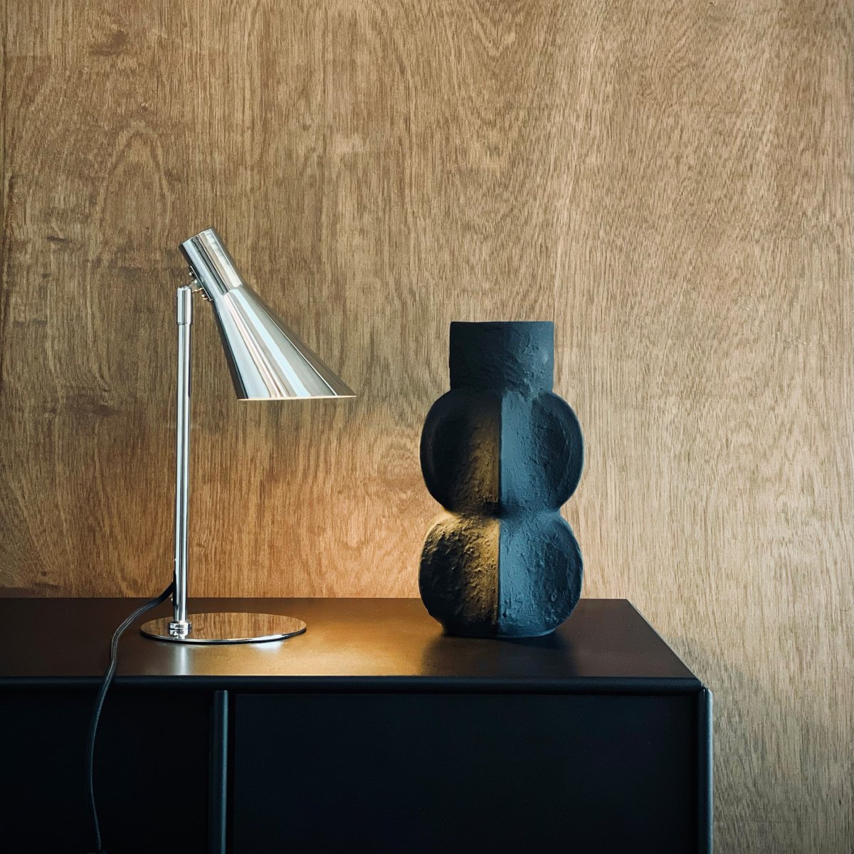 DL12 Mini 40cm Chrome lampe de bureau De Dyberg Larsen - Avec ses lignes graphiques distinctives et sa silhouette épurée, elle est idéale sur un bureau ou comme lampe de lecture dans le salon ou la chambre.
