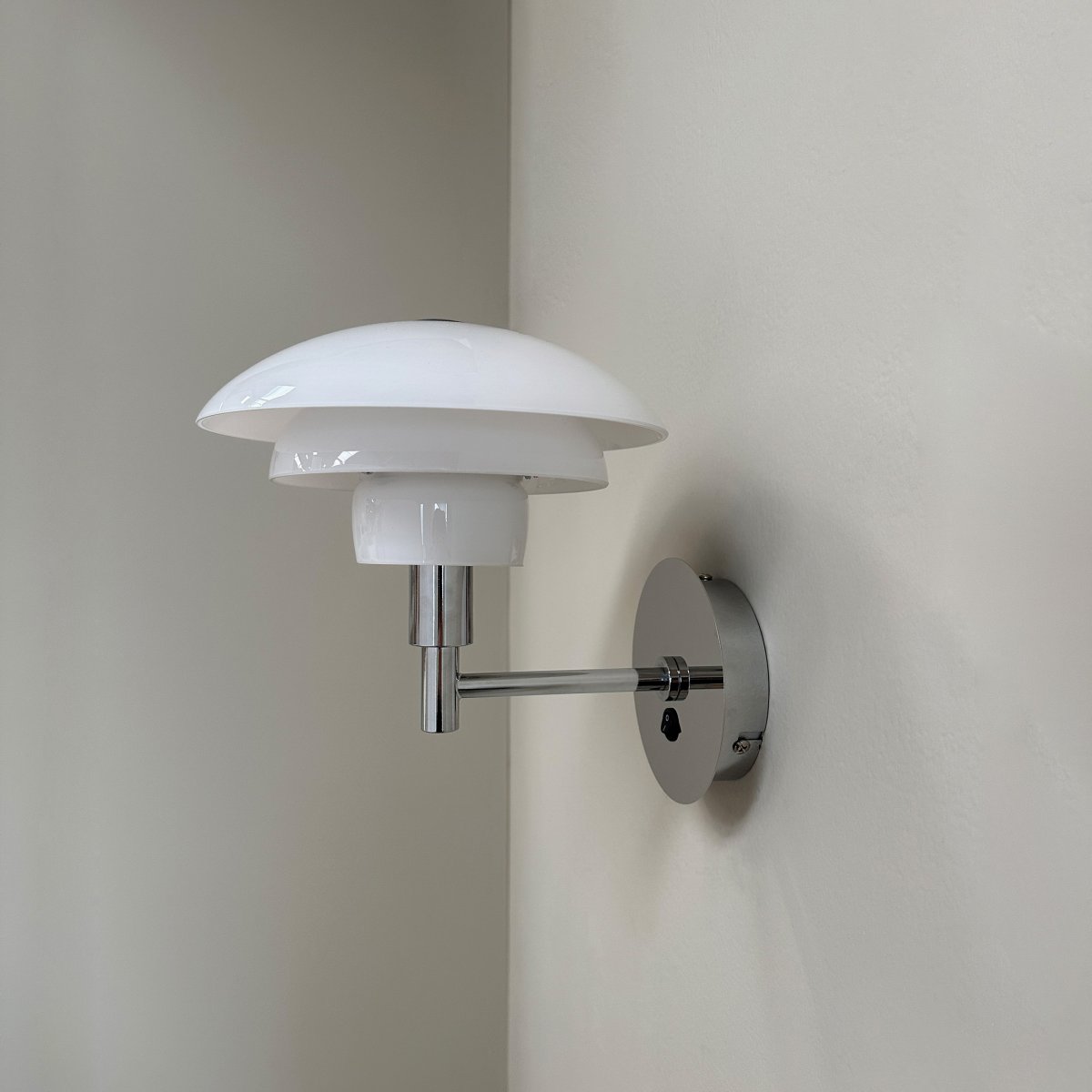 Morph Ø20 Chrome applique murale De Dyberg Larsen - L'applique murale Morph est fabriquée en verre opale blanc soufflé à la bouche avec un bras de lampe chromé et un support mural.