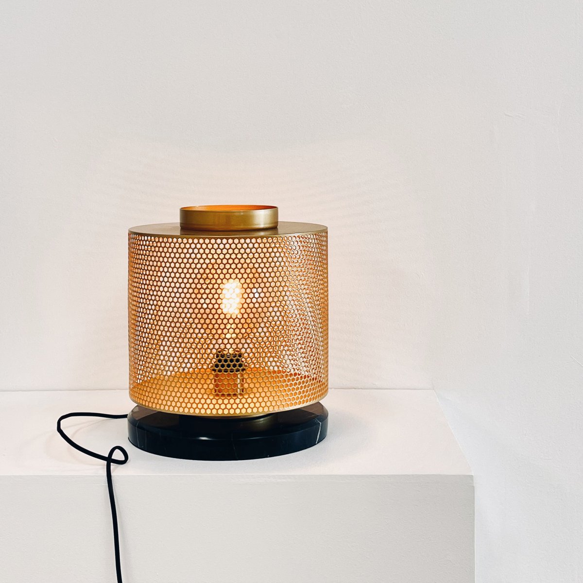 Nantes 35cm Laiton lampe de table De Dyberg Larsen - La lampe est conçue avec une belle maille hexagonale en laiton et une base en marbre noir, ce qui lui donne une brillance particulière et en fait un accroche-regard.