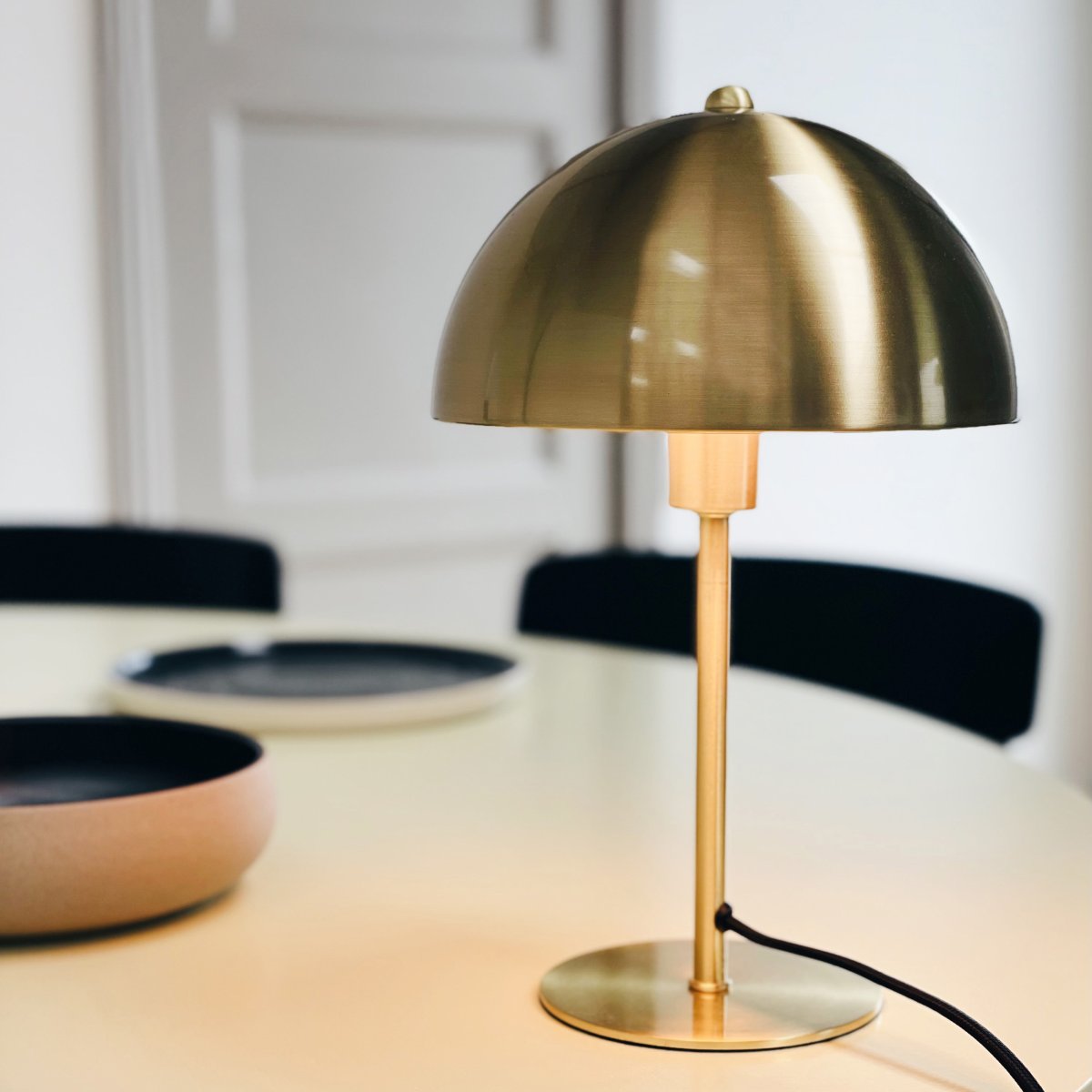 Lyon 30cm Laiton lampe de table De Dyberg Larsen - L'abat-jour semi-circulaire ajoute une touche moderne et assure une répartition lumineuse agréable et uniforme, idéale pour l'éclairage de travail et d'ambiance.