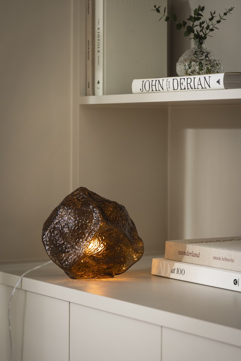 Valerie 22cm Brun lampe de table De Globen Lighting - Le verre soufflé à la main, avec sa surface texturée, capture la lumière, créant un jeu de lumière vibrant.