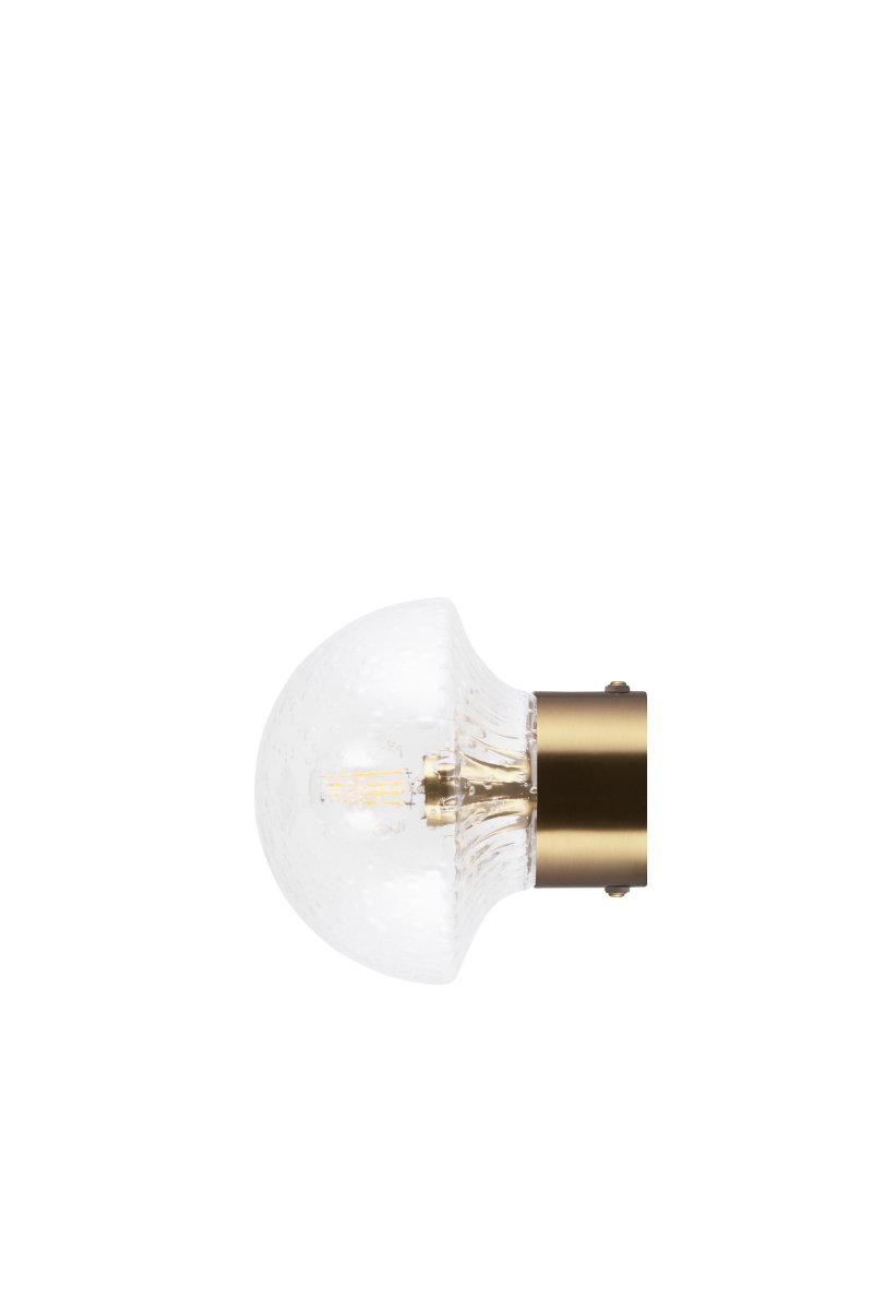 Fungo Ø16 Laiton transparent/brossé lampe de salle de bain De Globen Lighting - Son abat-jour en verre soufflé à la main, à la texture nervurée et aux bulles d'air, crée un magnifique jeu de lumière dans la pièce.