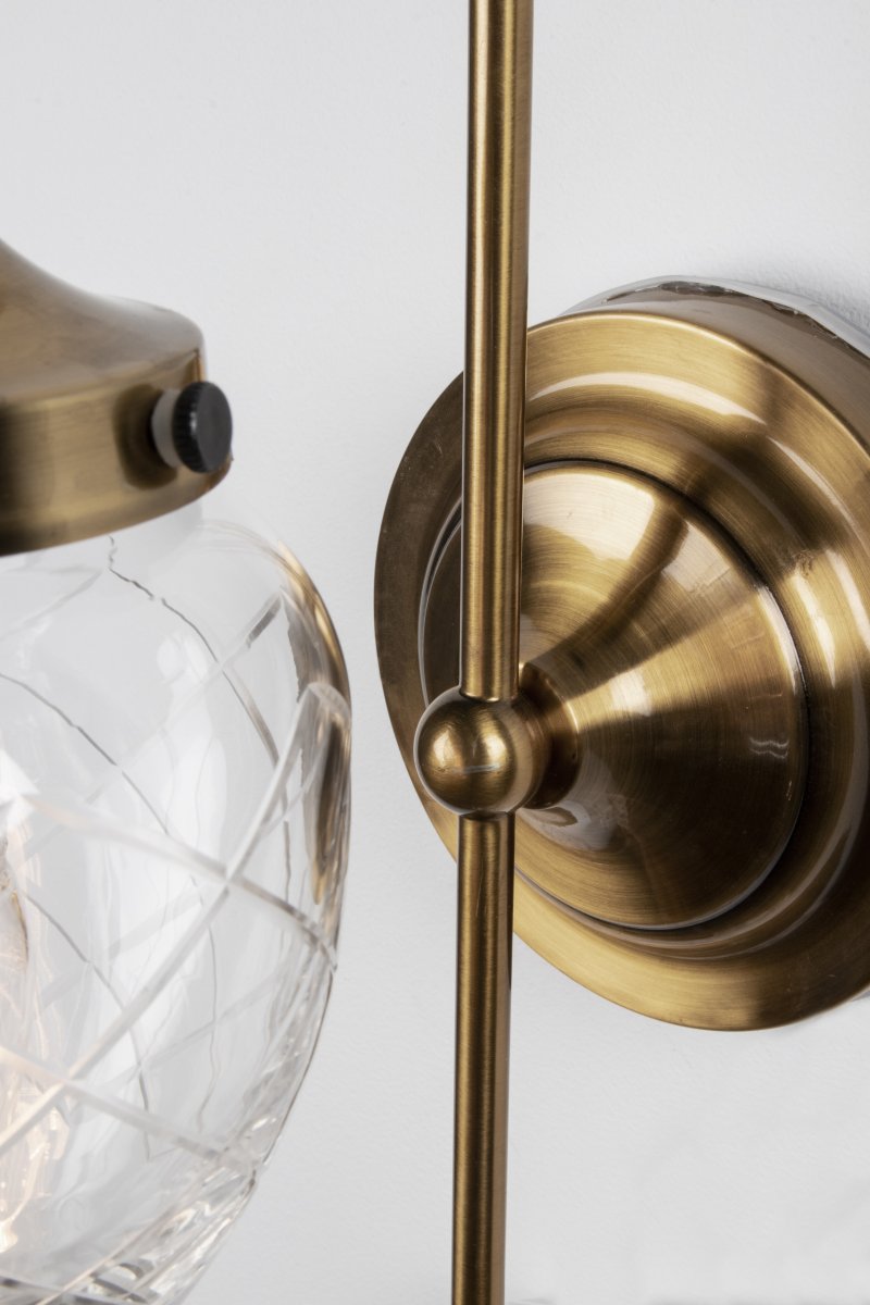 Juni 24cm Laiton antique/transparent lampe de salle de bain De Globen Lighting - Juni, avec son magnifique abat-jour en verre taillé et en métal, vous transporte au début du XXe siècle.