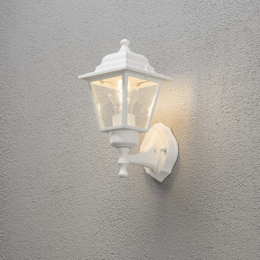 Vägglykta Blanc lampe d’extérieur De Konstsmide - Avec sa conception en forme de lanterne et ses panneaux en verre transparent, la lampe émet une lumière chaleureuse et invitante, parfaite pour les entrées, les patios et les allées.