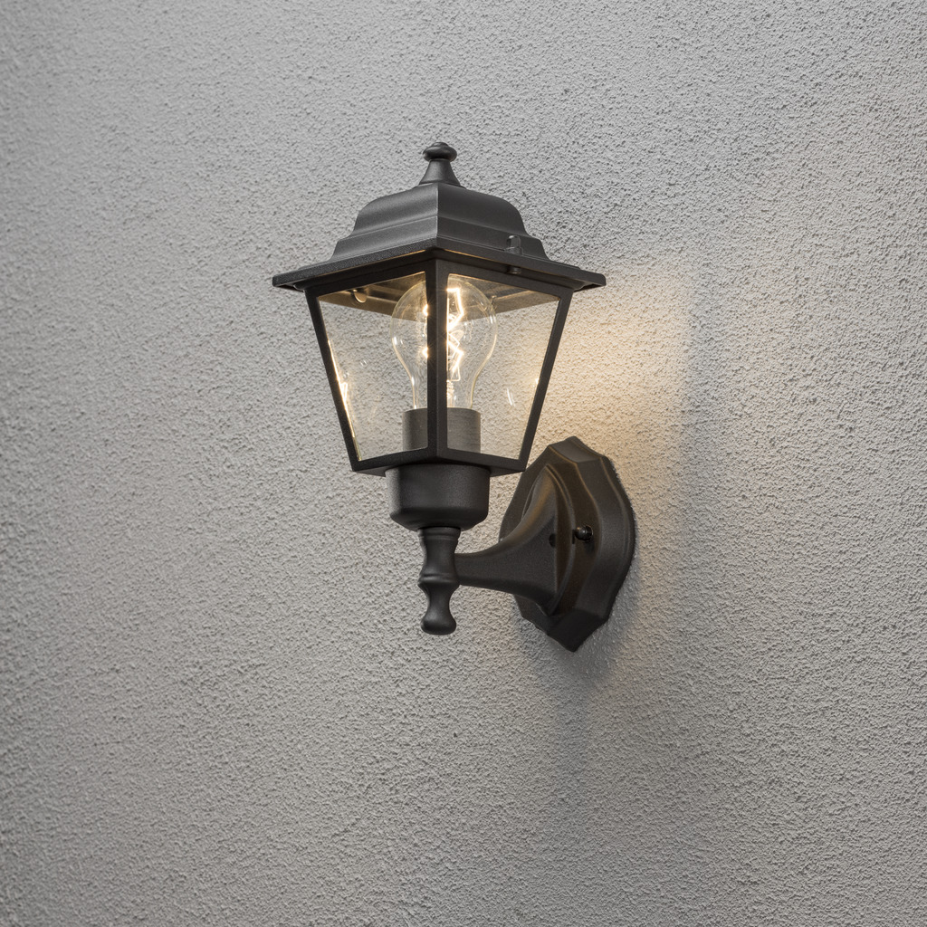 Vägglykta Noir lampe d’extérieur De Konstsmide - Avec sa conception en forme de lanterne et ses panneaux en verre transparent, la lampe émet une lumière chaleureuse et invitante, parfaite pour les entrées, les patios et les allées.