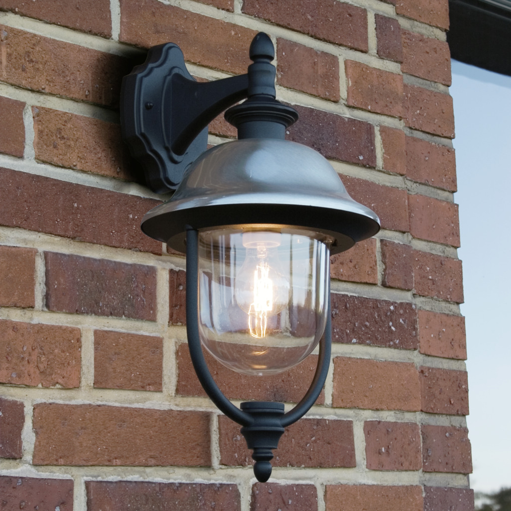 Parma Noir lampe d’extérieur De Konstsmide - Avec sa surface noire robuste et son abat-jour en verre transparent, il émet une lumière chaleureuse et invitante, créant une atmosphère accueillante à l'entrée ou sur la terrasse.