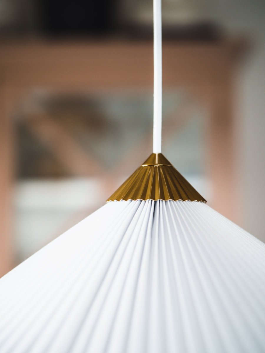 Matisse Ø60 Blanc suspension De Globen Lighting - La lampe est dotée d'un abat-jour en textile blanc plissé et est décorée d'un dessus plissé assorti en métal couleur laiton.