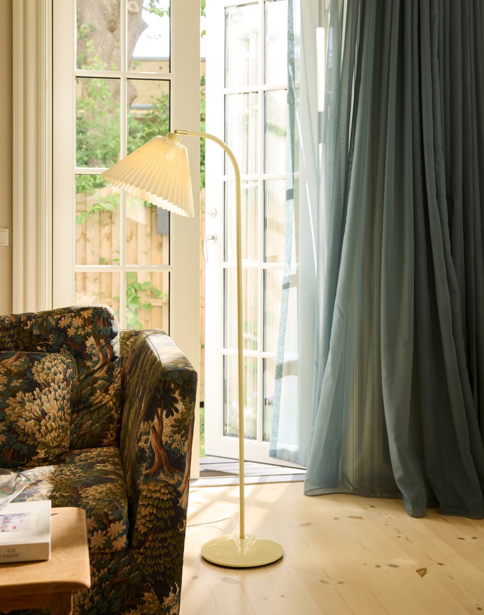 Medina Blanc crémeux lampadaire De Halo Design - Sa structure en métal blanc crème est mise en valeur par un magnifique abat-jour plissé en tissu assorti et des détails décoratifs en laiton.