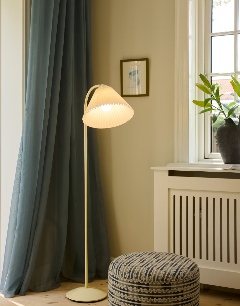 Medina Blanc crémeux lampadaire De Halo Design - Sa structure en métal blanc crème est mise en valeur par un magnifique abat-jour plissé en tissu assorti et des détails décoratifs en laiton.
