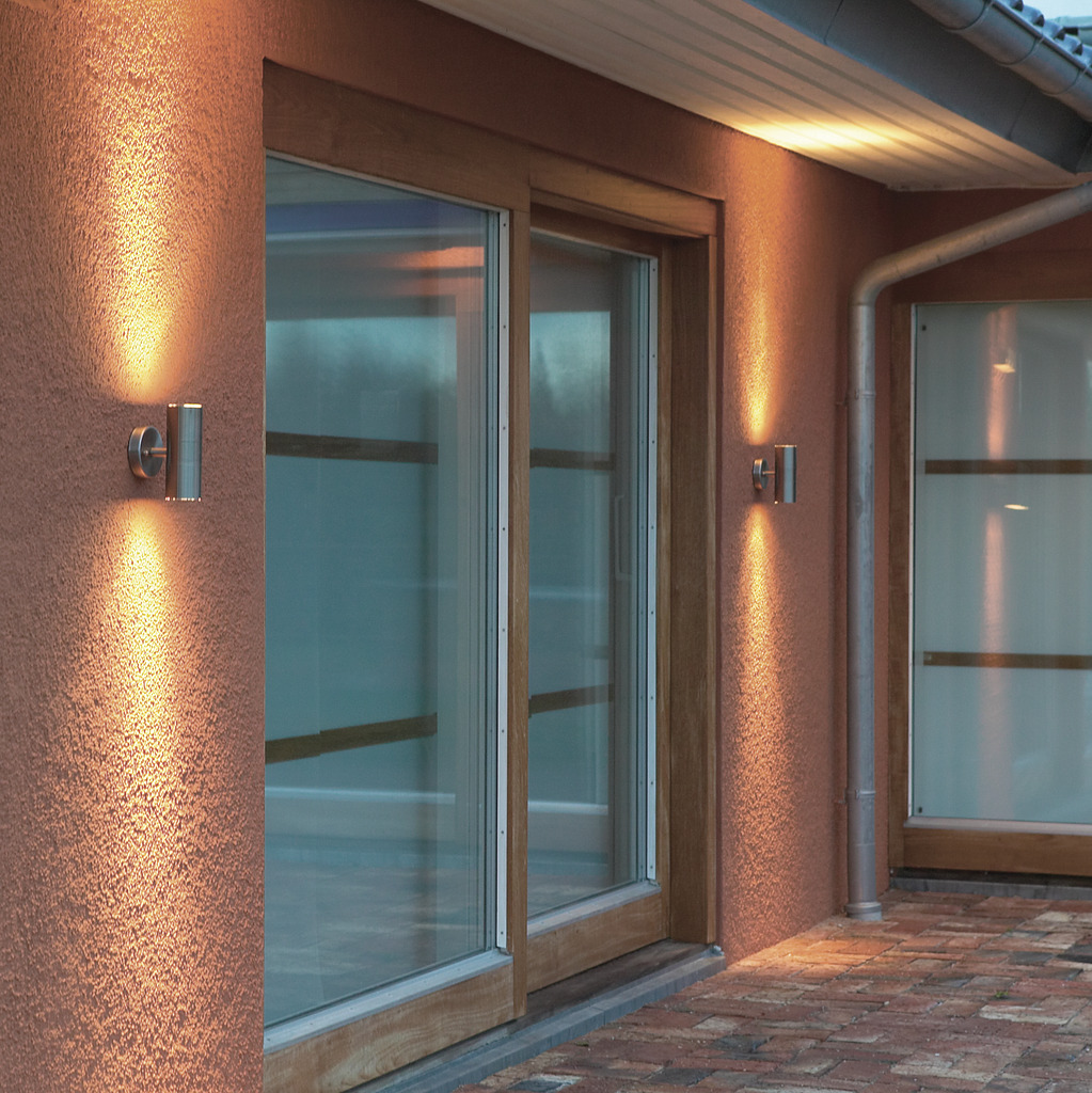 Modena Argent lampe d’extérieur De Konstsmide - Le design minimaliste avec des détails en verre transparent ajoute une touche sophistiquée et crée un beau jeu de lumière qui met en valeur la façade.