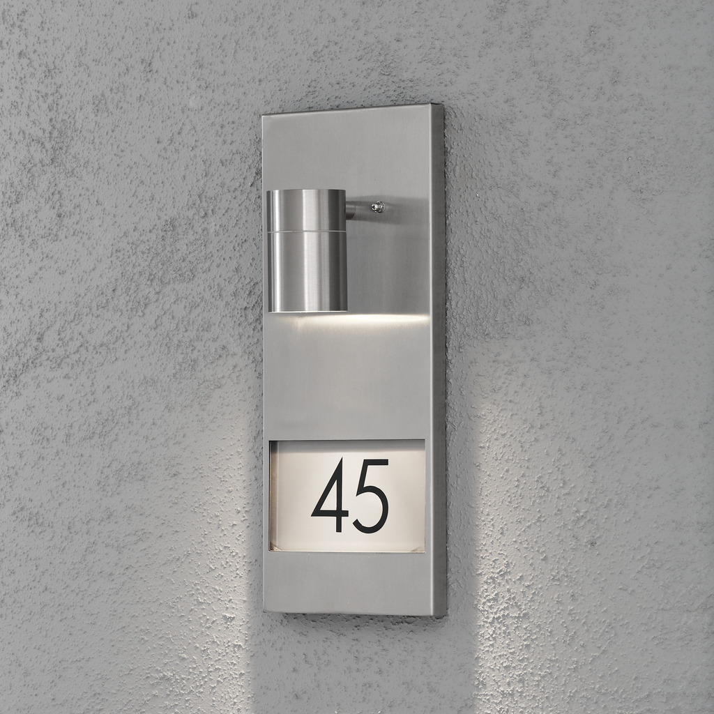 Modena Argent lampe d’extérieur De Konstsmide - Avec son design moderne en acier inoxydable et son éclairage orienté vers le bas, il met clairement en valeur votre numéro de maison même dans les heures les plus sombres de la journée.